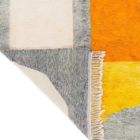 Close-up view of the geometric pattern and fringe edge of the gray and orange color block rug.