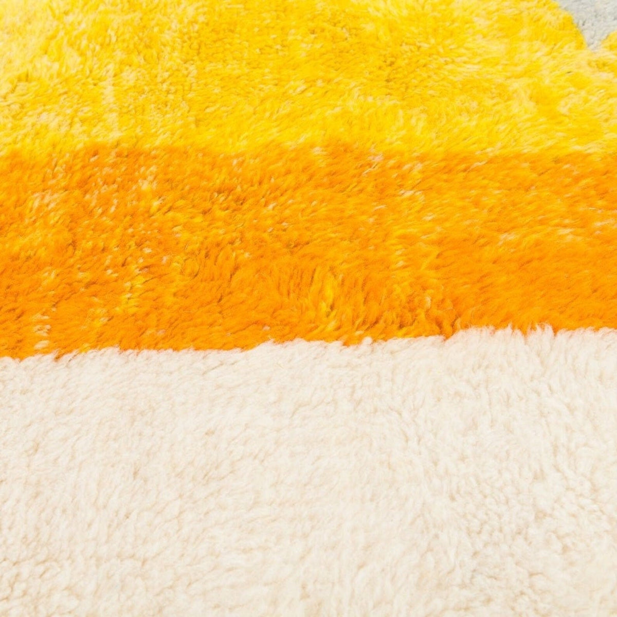 Close-up detail of the fringe edges of the gray and orange color block rug.