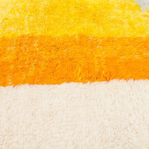 Close-up detail of the fringe edges of the gray and orange color block rug.