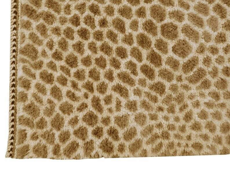 Detail close-up of a brown and cream geometric patterned rug on a white background.
