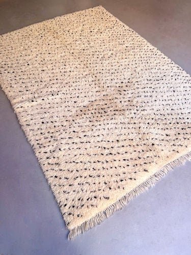Lifestyle shot of the gray and cream Moroccan Beni Ourain rug displayed in a studio setting.