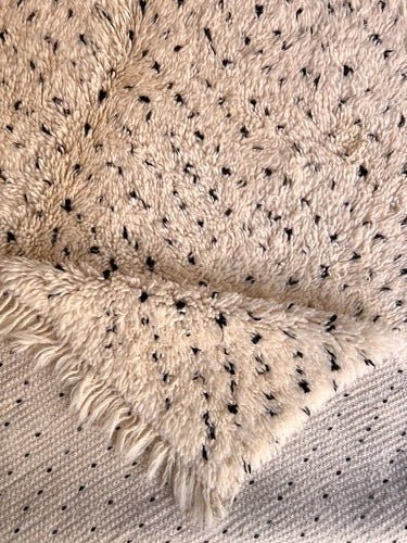 Close-up detail of the patterned weave and fringe of the gray and cream Moroccan Beni Ourain rug.