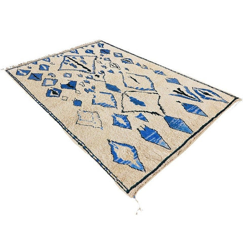 Close-up detail of a blue Berber rug with intricate designs and a textured surface.