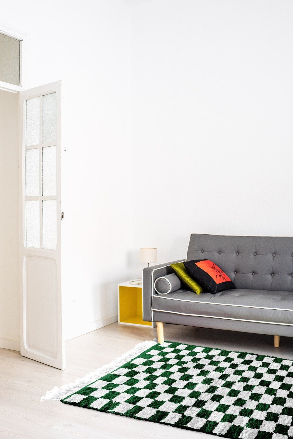 Lifestyle shot of the green checkered Moroccan rug with a sofa and decorative pillows.