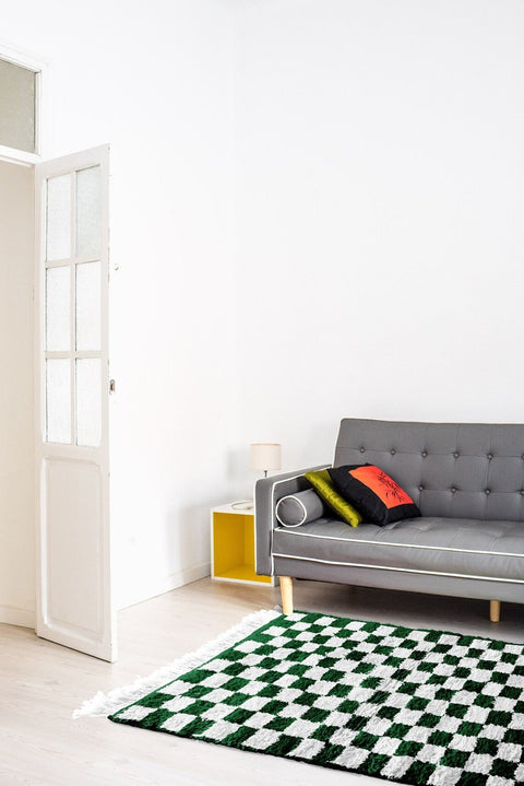 Lifestyle shot of the green checkered Moroccan rug with a sofa and decorative pillows.