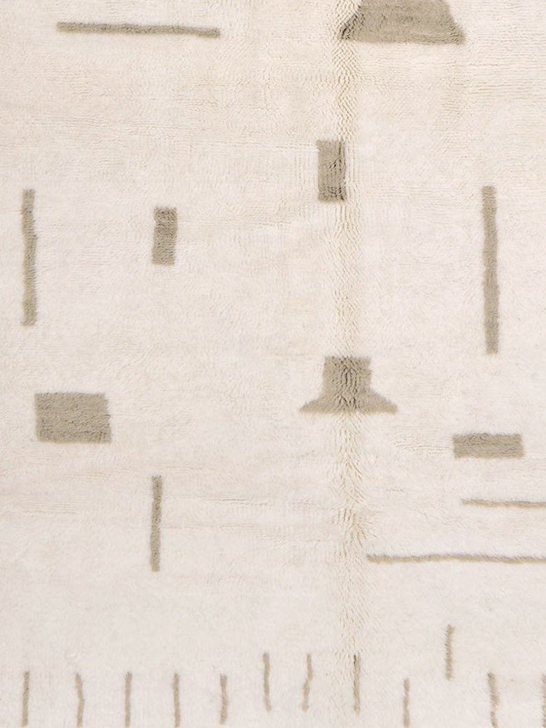 Front view of an off-white gray Moroccan rug with a geometric design and fringe edges.