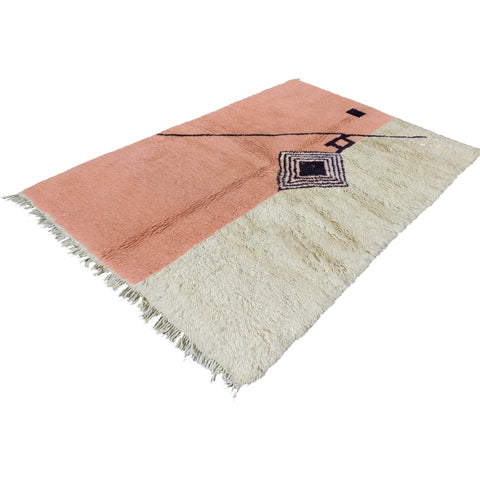Close-up detail of the pink geometric pattern rug with fringe edges.