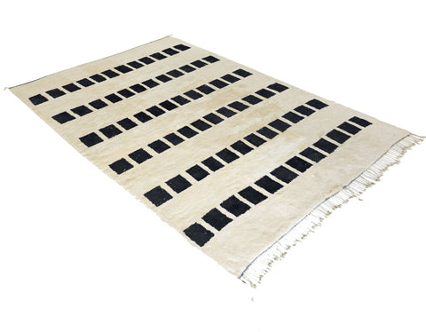 Side view of the black and white Moroccan rug featuring geometric patterns and fringe edges.