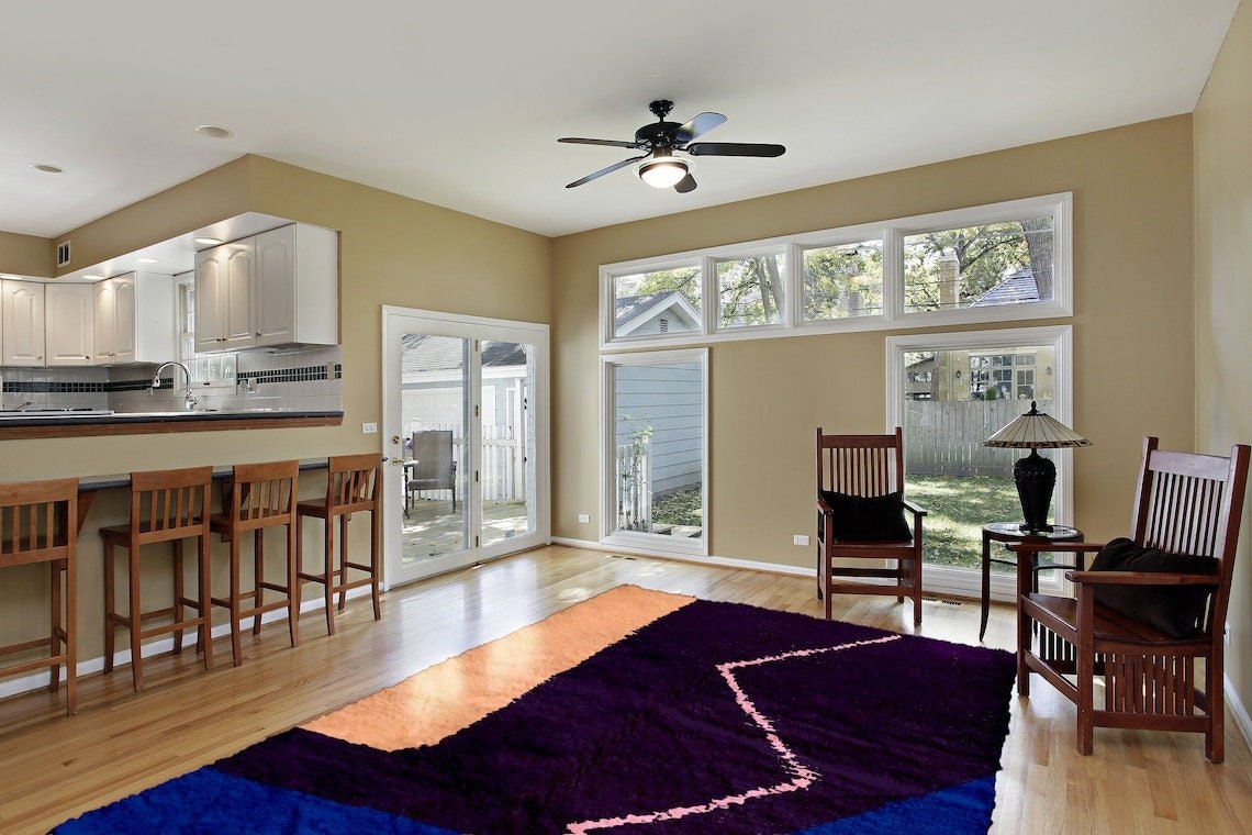 Lifestyle shot of a living room featuring a purple and blue abstract Moroccan rug with wooden furniture.