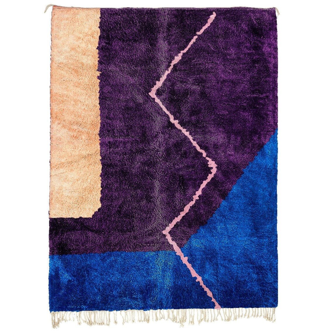 Detail close-up of a purple and blue abstract Moroccan rug with a geometric pattern.