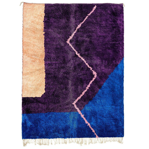 Detail close-up of a purple and blue abstract Moroccan rug with a geometric pattern.