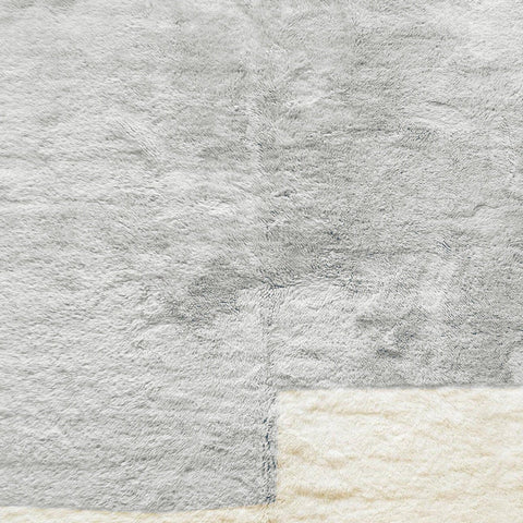 Detail close-up of the textured surface and fringe edges of the gray and white Moroccan rug.