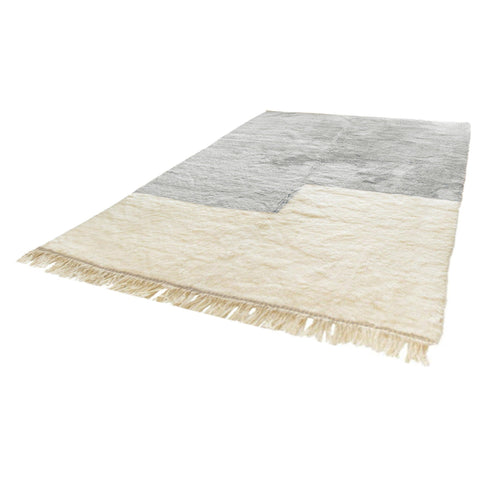 Side view showcasing the gray and white Moroccan rug's fringe edges and textured surface.