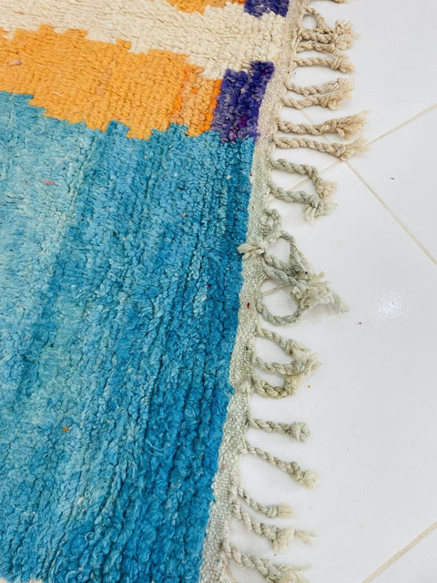 Detail close-up of the rug edge highlighting fringe edges with blue and orange colors.