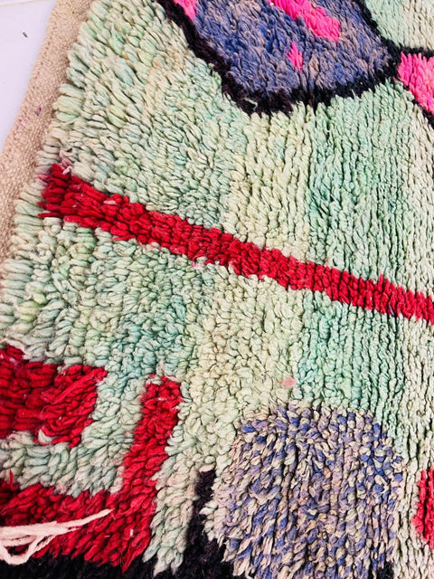 Detail view of a colorful Moroccan rug showcasing vibrant patterns in green, red, orange, and pink.