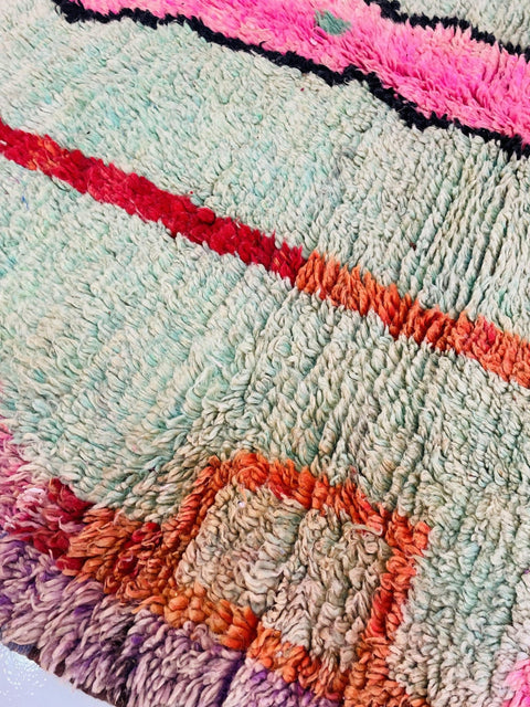 Close-up of an abstract Moroccan rug with a textured surface in blue, red, orange, and pink.