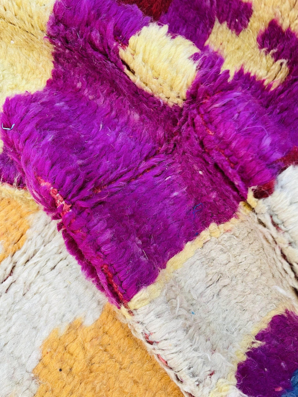 Top angle of the abstract Moroccan rug displaying vibrant blue and red colors with fringe edges.