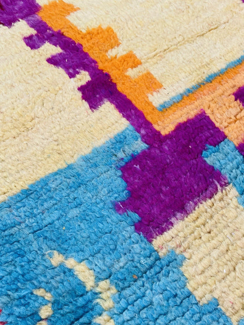 Close-up detail of the abstract Moroccan rug featuring blue, orange, and purple colors.