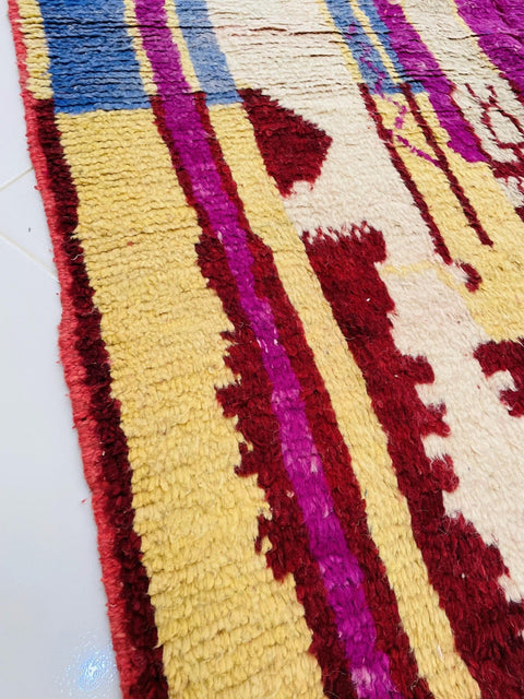 Close-up detail of the abstract Moroccan rug showcasing red, purple, and beige colors.