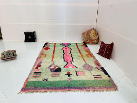 Lifestyle view of a vibrant Moroccan rug showcasing abstract patterns in green, pink, black, and red.
