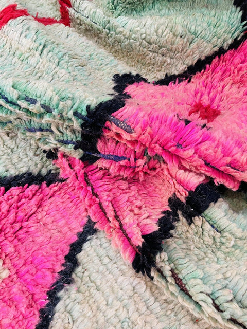 Close-up detail of the edge of a colorful Moroccan rug with fringe and vibrant patterns.