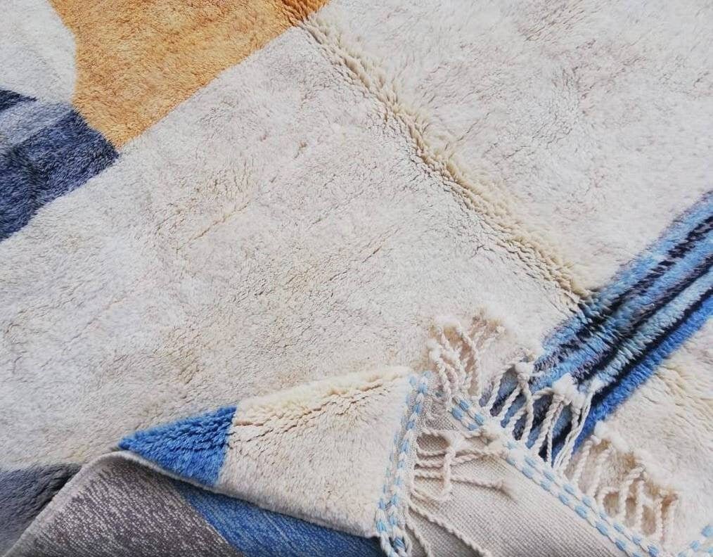 Lifestyle view of a geometric Moroccan rug featuring blue and orange colors.