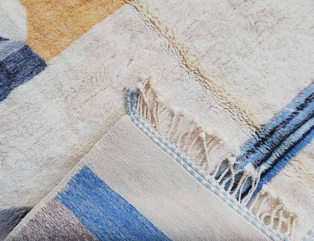 Close-up detail of the textured surface of a blue and orange geometric Moroccan rug.