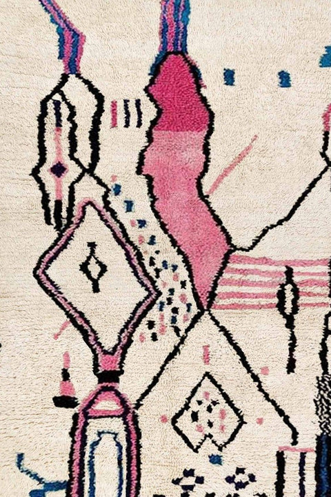 Detail close-up of a multicolor tribal pattern Moroccan rug highlighting geometric designs in pink, beige, and blue.