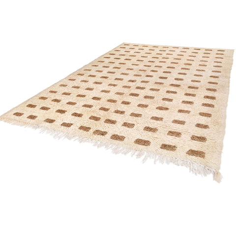 Side view of the warm beige Beni Ourain rug showcasing its fringed edges.