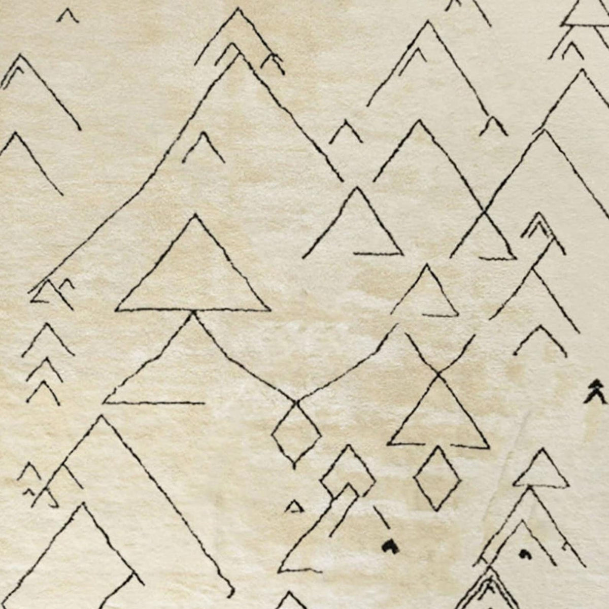 Detail close-up of the off-white Moroccan rug highlighting geometric patterns and fringed edges.