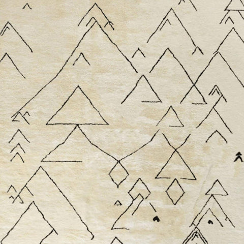 Detail close-up of the off-white Moroccan rug highlighting geometric patterns and fringed edges.