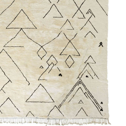 Side view of the off-white Moroccan rug displaying geometric patterns and fringed edges.