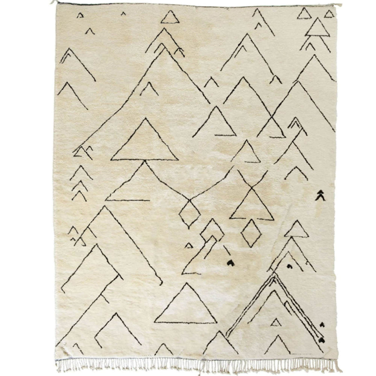 Detail close-up of the off-white Moroccan rug showcasing geometric patterns and fringed edges.