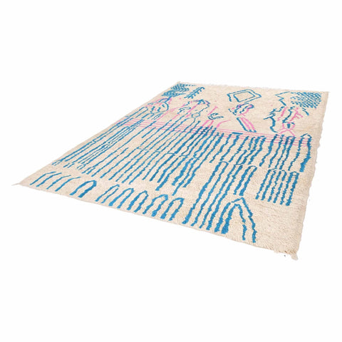 Side view of an abstract Moroccan rug showcasing its beige, blue, and pink design.