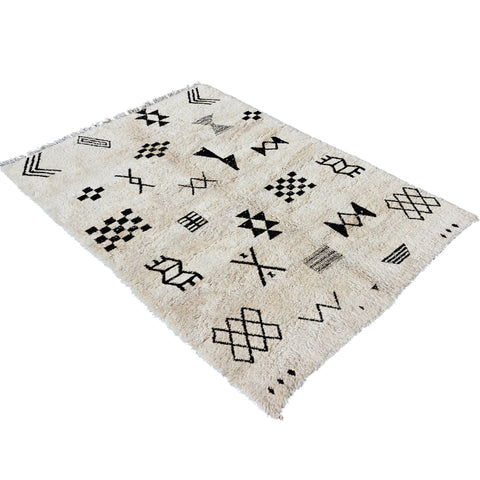 Lifestyle shot of a black and white Moroccan Tribal Custom Rug with tribal patterns on a natural background.