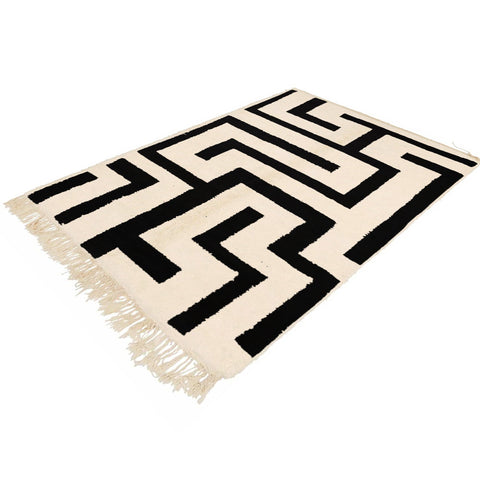 Lifestyle shot of the black and white labyrinth rug showcasing its geometric design in a room setting.