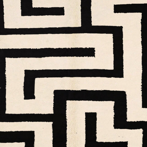 Detail close-up of the black and white labyrinth rug with geometric patterns and fringe edges.