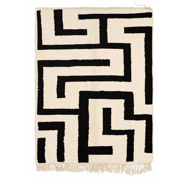 Detail close-up of the black and white labyrinth rug featuring geometric patterns and fringe edges.