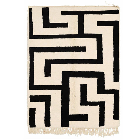 Detail close-up of the black and white labyrinth rug featuring geometric patterns and fringe edges.
