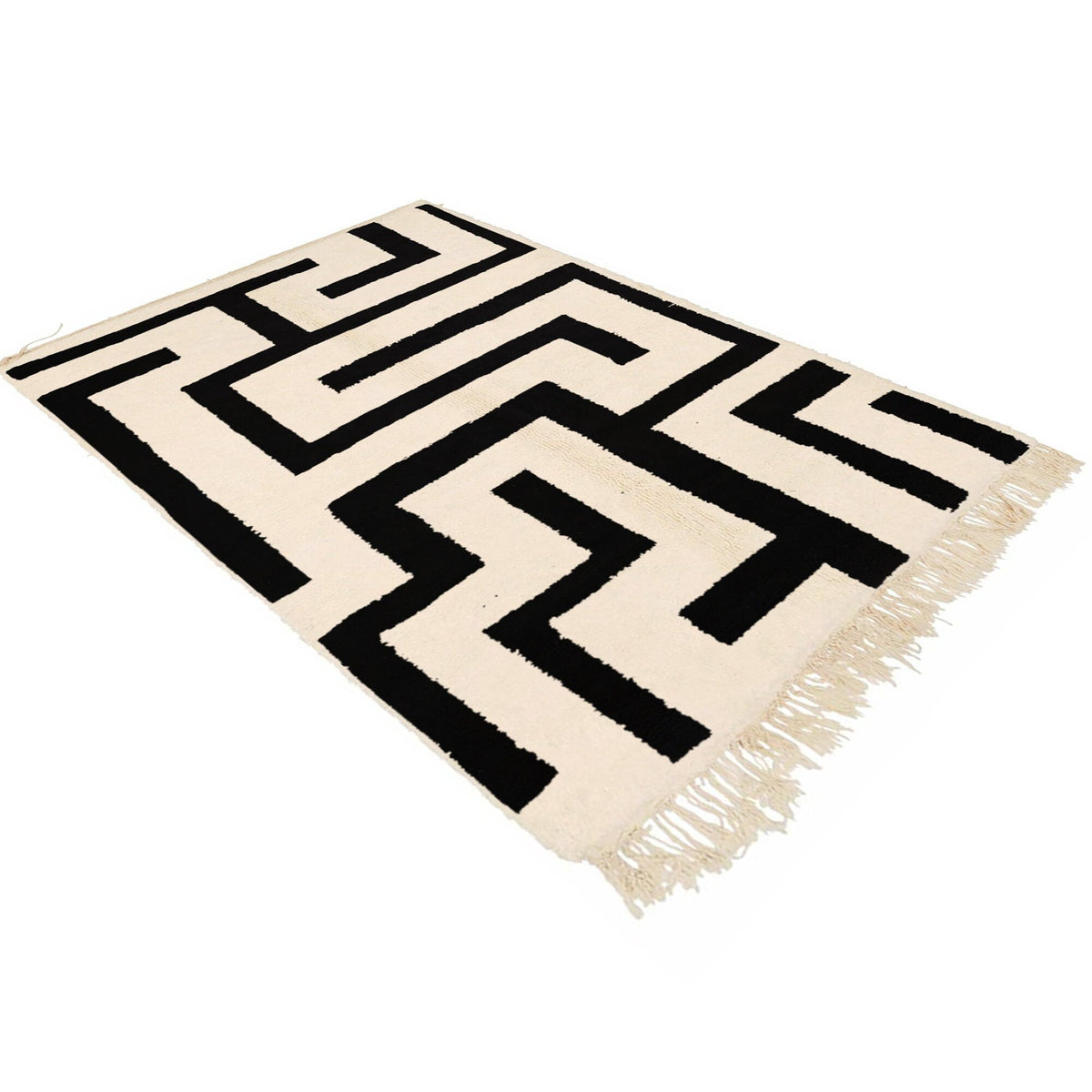 Lifestyle view of the black and white labyrinth rug highlighting its geometric pattern and fringe edges.