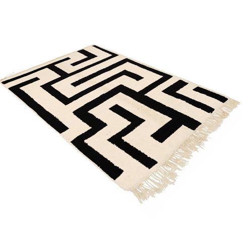 Lifestyle view of the black and white labyrinth rug highlighting its geometric pattern and fringe edges.