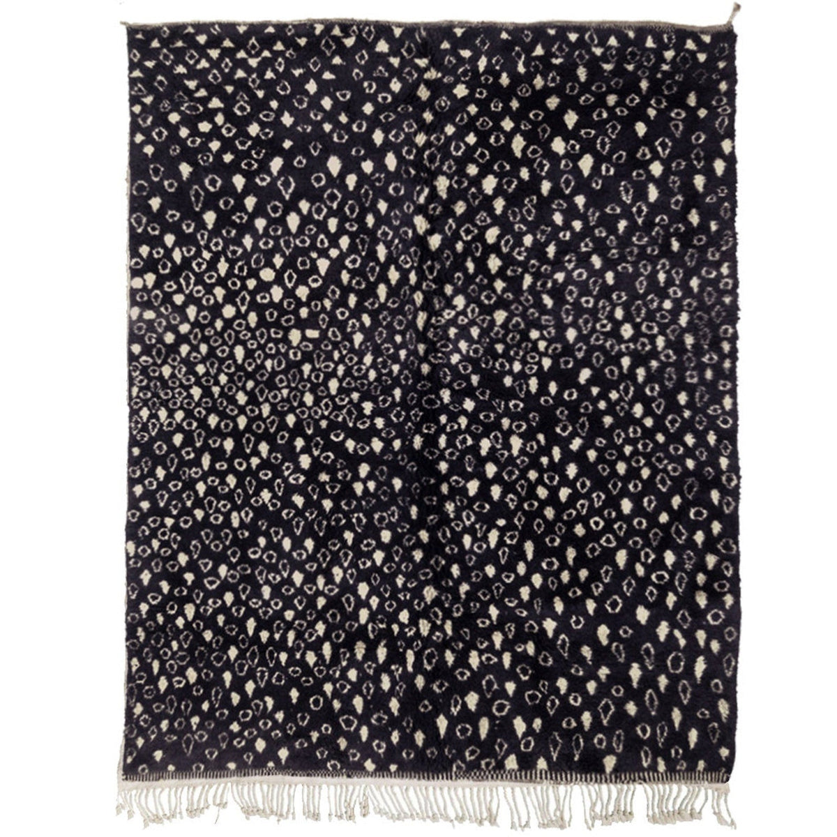 Detail close-up of a textured black and beige abstract rug with fringe edges.