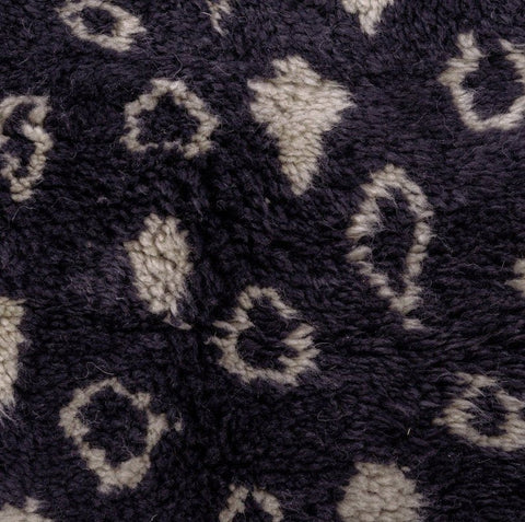 Detail close-up of a black and beige abstract rug featuring a leopard print.