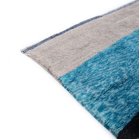 Detail view of the abstract area rug with a striped pattern in blue and beige.