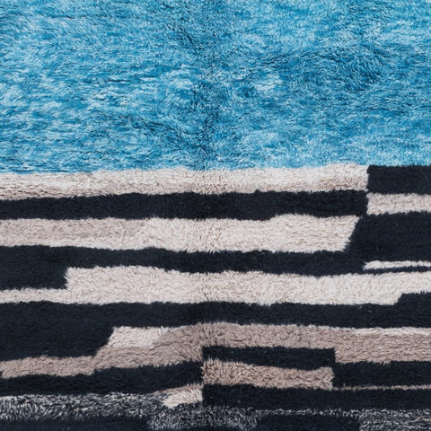 Detail shot of the blue and charcoal area rug featuring a soft texture and striped design.