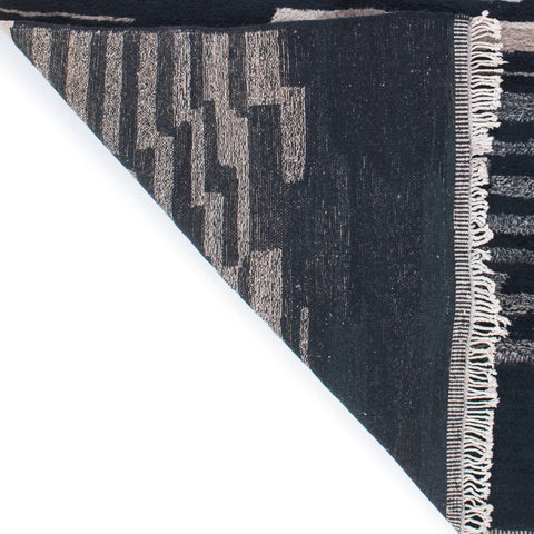 Angled view of the abstract area rug highlighting its textured surface in blue and beige.