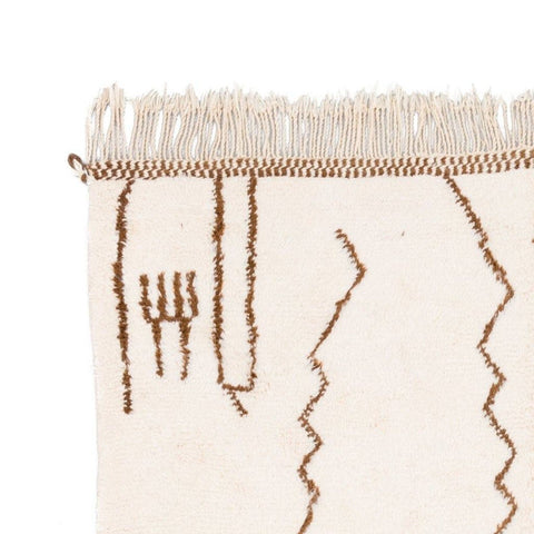 Close-up detail of the off-white rug featuring fringe detail and an abstract pattern.