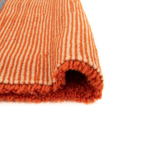 Close-up detail of the orange rug showing its textured surface and rolled edge.