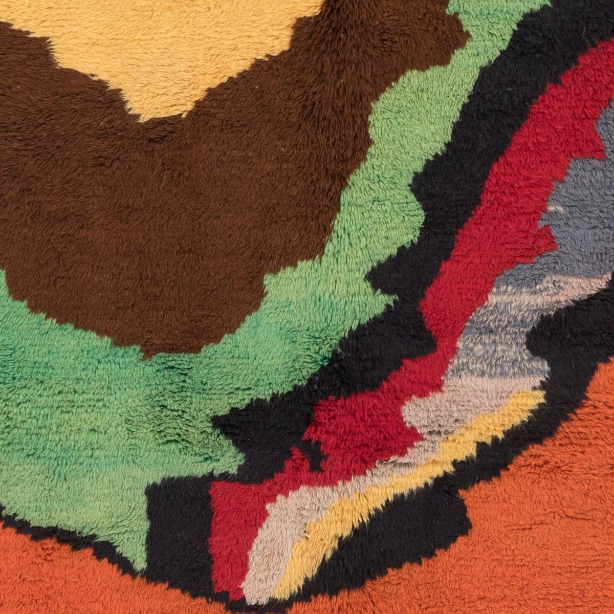 Close-up of the texture of the orange rug with colorful patterns.