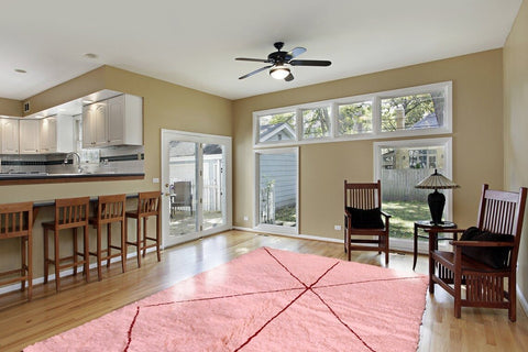 Lifestyle shot of the pink Moroccan Berber rug in a living room setting with wooden flooring and large windows.